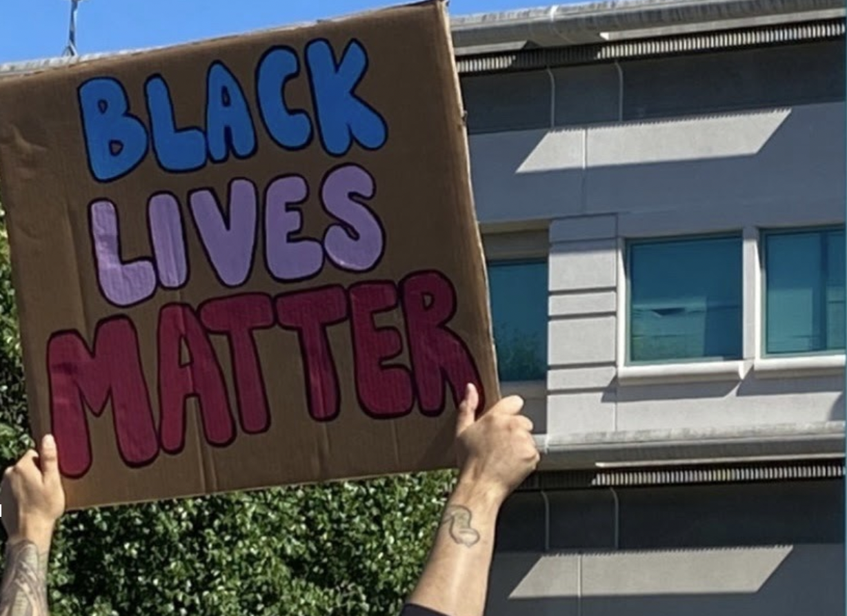 A Black Lives Matter cardboard sign being held up.