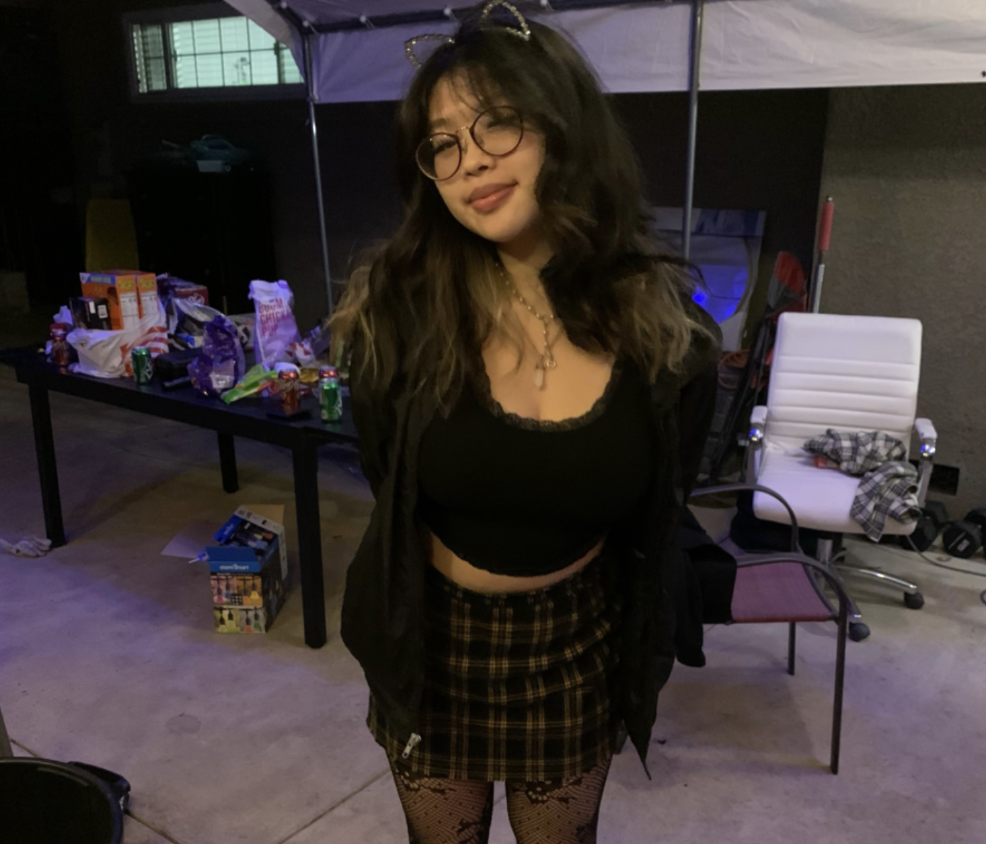 Senior Iris Shih wearing cat ears, a low-necked black crop top with a black jacket, a plaid skirt, and transparent leggings.