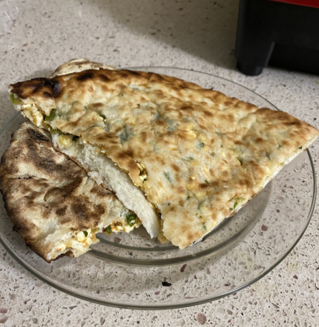 Garlic naan on a glass plate, which lies on a speckled countertop.