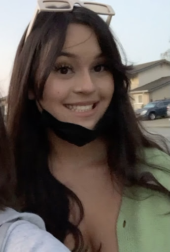 Kaitlyn Lagrimas, with her mask off, cream-colored sunglasses on her forehead, in a green shirt, smiling.