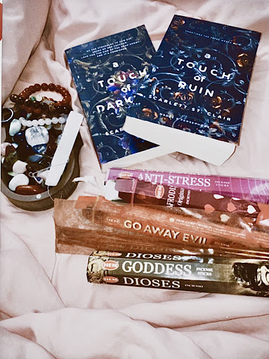 Books titled 'a Touch of Dark' and 'Go Away Evil' as well as an ensemble of bracelets and crystals.